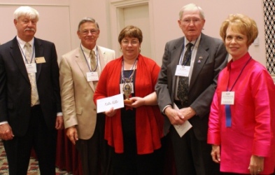 McHenry County College student Kathi Miller (third from accepts her $500 Paul Simon Student Essay Contest scholarship from Illinois Community College System Foundation board member Tom Pulver (far left), ICCSF board member Jim Berkel, ICCSF president Dr. Ray Hancock, and ICCSF board member Dr. Alice Marie Jacobs.