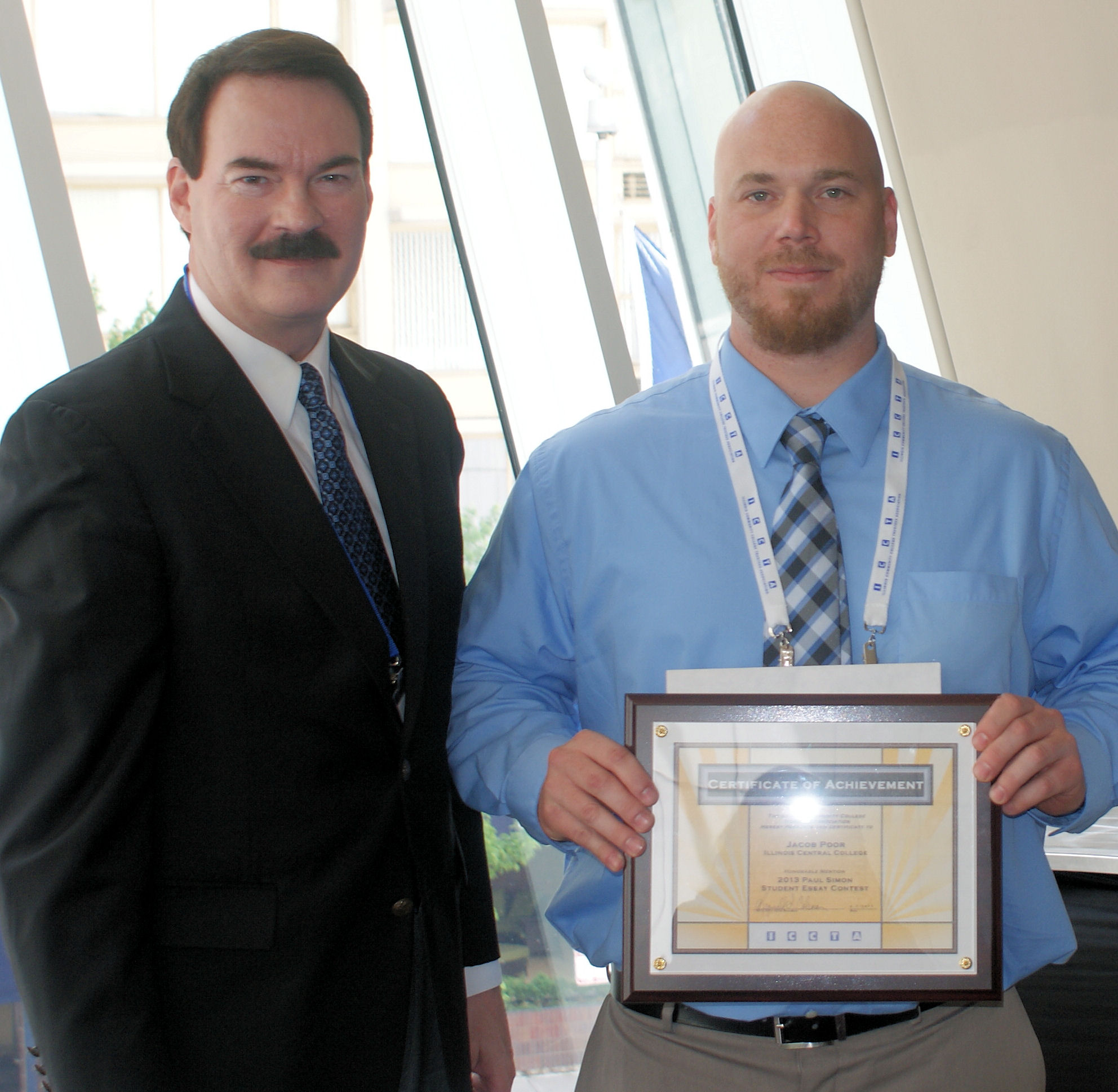 Illinois Central College student Jacob Poor (right) accepts his $250 Paul Simon Student Essay Contest scholarship from ICC president Dr. John Erwin.