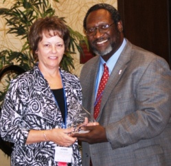 Illinois Valley Community College board secretary Jeanne Hayden accepts ICCTA's Professional Board Staff Member Award from ICCTA vice president Reggie Coleman.
